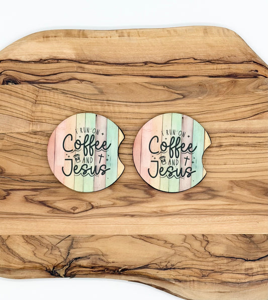 Two round coasters with a pastel wood-plank design and the text 'Run on Coffee and Jesus' laid on a large wooden serving board.