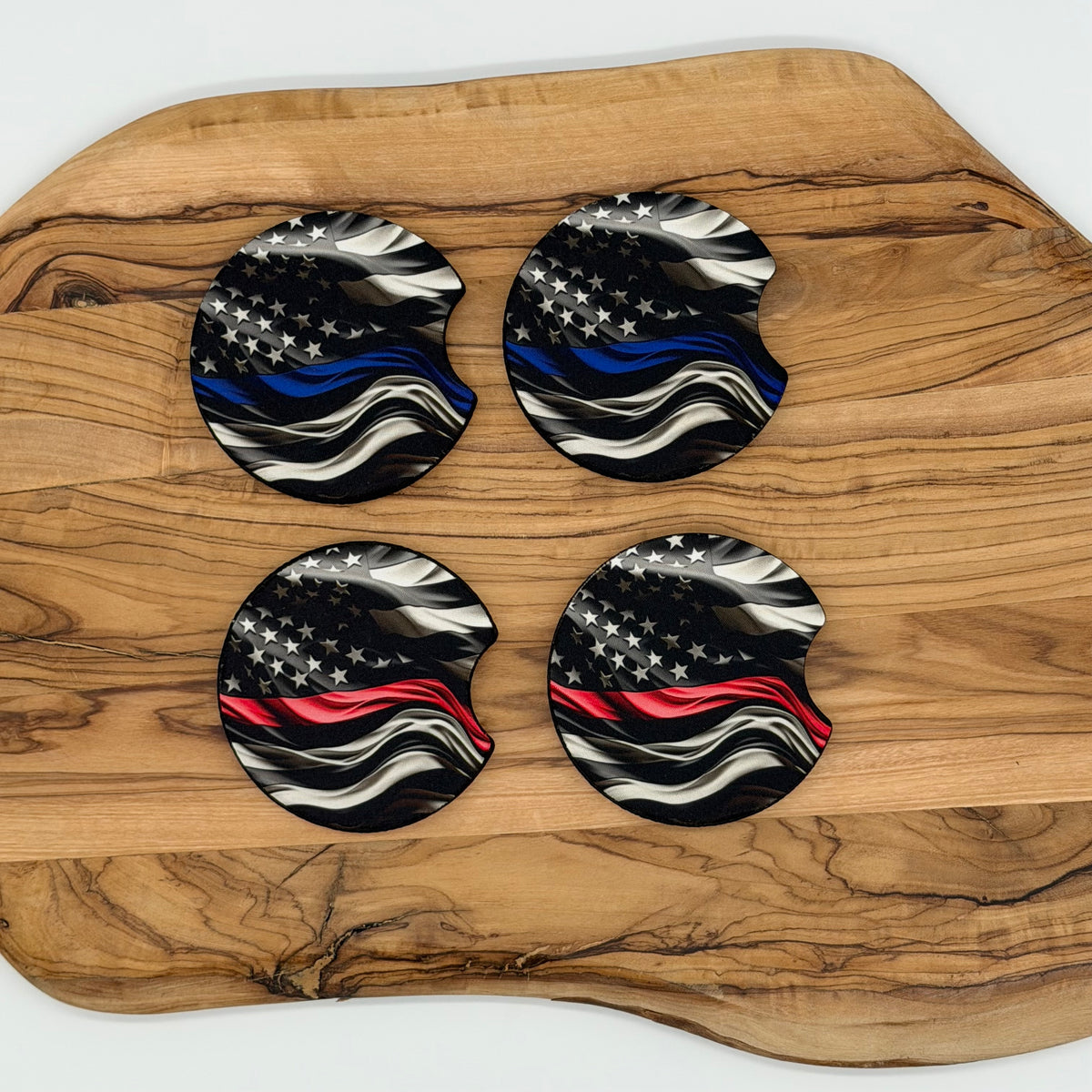 Four circular coasters with a black, white, and blue American flag design featuring a thin red line, arranged on a natural wood serving board.